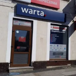 Fasada biura Warta z ofertą różnych typów ubezpieczeń widoczną na szybie, w tym komunikacyjne, mieszkaniowe, rolne, turystyczne, firmowe i na życie.
