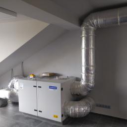 AKA KOMFORT - Szara instalacja wentylacyjna Komfovent Verso z izolowanymi rurami w pomieszczeniu na poddaszu w Raszynie, widoczne podłączenia elektryczne i skrzynka sterownicza.