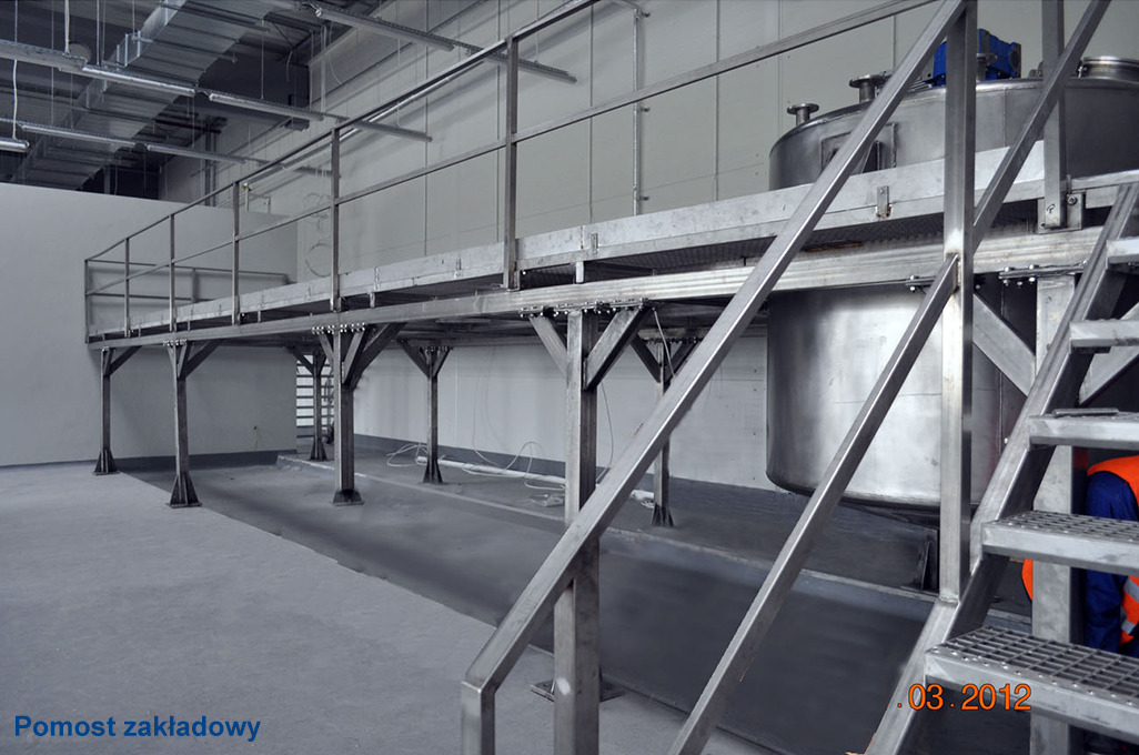Konstrukcja stalowa pomostu roboczego z zbiornikami ze stali nierdzewnej w hali produkcyjnej, Złoty Stok. Metalowe schody i barierki.