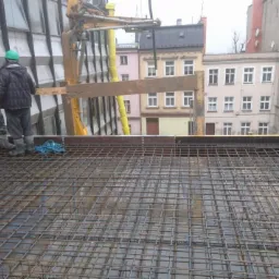 Zbrojenie stropu z siatki stalowej przygotowane pod wylewkę betonu, widok z góry, pracownicy w odzieży roboczej w tle, Zabierzów Bocheński.