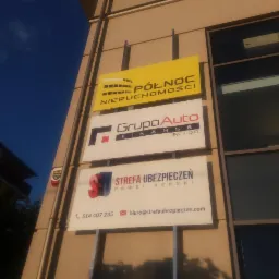 Zewnętrzny szyld reklamowy z logo firm: Północ Nieruchomości, Grupa Auto Finanse i Strefa Ubezpieczeń Paweł Dębski, umieszczony na ścianie budynku biurowego.