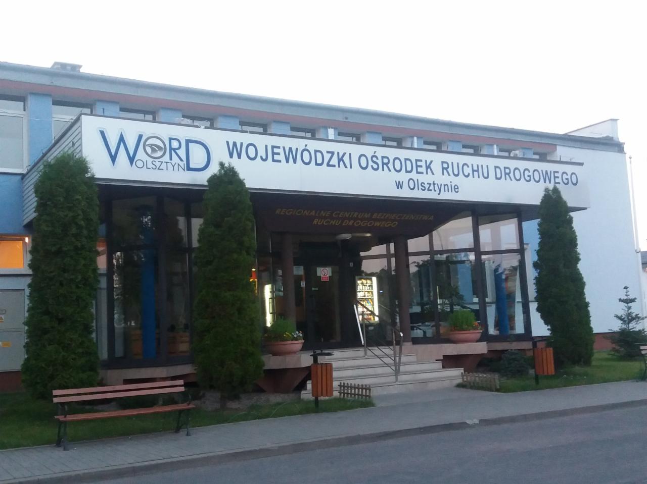 Budynek Wojewódzkiego Ośrodka Ruchu Drogowego w Olsztynie z widocznym logo WORD nad wejściem i zielenią przed budynkiem.