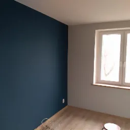 Pomieszczenie po odświeżeniu: granatowa ściana kontrastuje z białymi ścianami i oknem, na podłodze leżą kable.