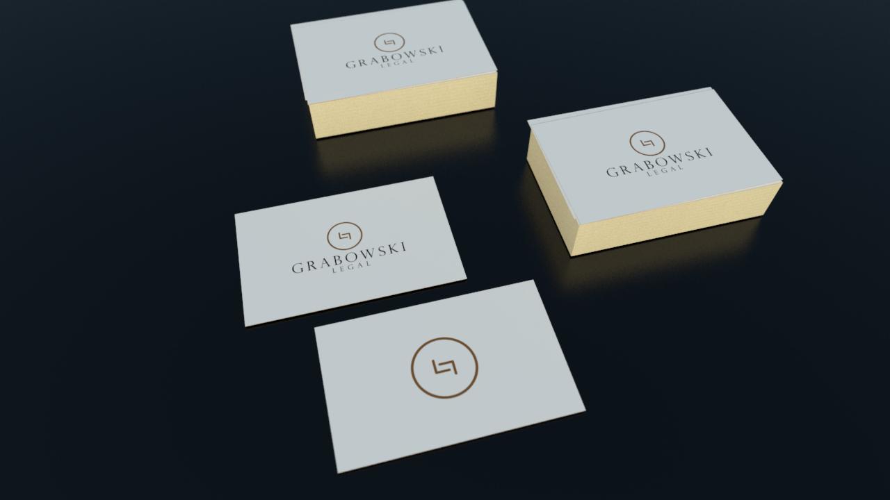 Wizytówki kancelarii prawnej Grabowski Legal z logo i złotymi brzegami, ułożone na ciemnym tle.