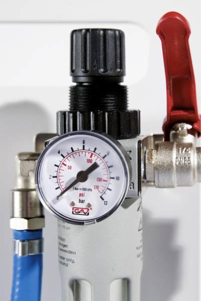 Zbliżenie na regulator ciśnienia z manometrem wskazującym około 100 psi, podłączony do niebieskiego przewodu, z czerwoną dźwignią zaworu, na tle białej ściany.