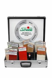 Otwarta aluminiowa walizka prezentująca zestaw próbek impregnatów do powierzchni Scheidel, z centralnym logo i różnymi kolorami i fakturami próbek wewnątrz.