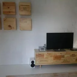 Stolik RTV z frontami z drewnianych skrzynek po winie i drewniane dekoracje ścienne w aranżacji wnętrza. Unikalny design mebla.