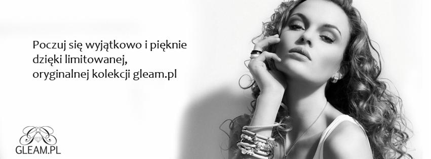 Czarno-białe portretowe ujęcie modelki z kręconymi włosami, prezentującej bransoletki z jasnych koralików na nadgarstku, pierścionek na palcu i subtelny makijaż.