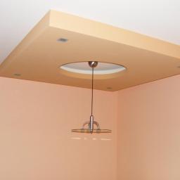 Zakład Remontowo Budowlany Piotr Kogut - Kwadratowa zabudowa sufitowa z okrągłym otworem na lampę wiszącą, wbudowane halogeny, ściany w odcieniach brzoskwini.