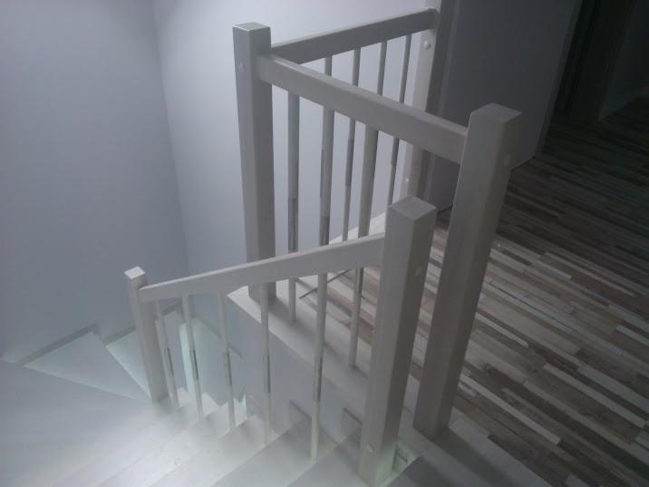 Białe schody z drewnianą balustradą, widok z góry, parkiet w tle.