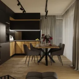 Nowoczesna jadalnia z drewnianym stołem na metalowej podstawie, otoczona szarymi krzesłami, z widokiem na kuchnię z drewnianymi szafkami i czarnymi frontami, oświetlona reflektorami.