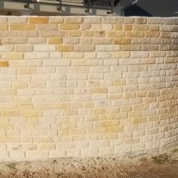 Jar-bud - Zakrzywiony murek z piaskowca, fragment ogrodzenia posesji z elementami śniegu na ziemi.