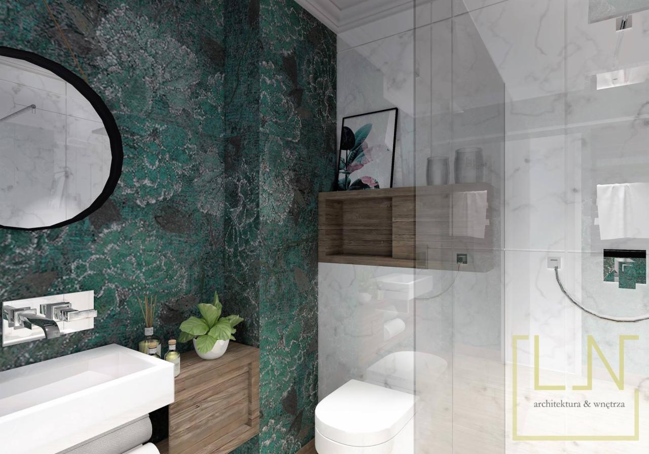 Wizualizacja łazienki z zieloną ścianą w roślinny wzór, okrągłe lustro, biała umywalka i toaleta, drewniana szafka pod umywalką z zieloną rośliną doniczkową, szklana kabina prysznicowa z białymi...