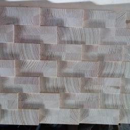 dor san art - Dekoracyjna ściana z drewnianych, jasnych klocków o widocznym usłojeniu, ułożonych w nieregularny wzór.