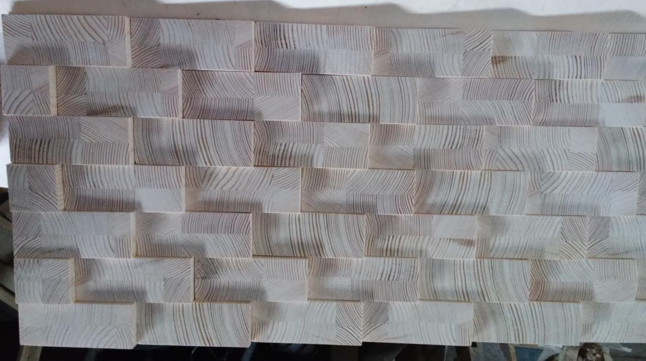 Dekoracyjna ściana z drewnianych, jasnych klocków o widocznym usłojeniu, ułożonych w nieregularny wzór.