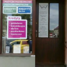 Wejście do biura kredytowego z naklejkami informacyjnymi o dostępnych kredytach: gotówkowych, konsolidacyjnych, dla firm, pozabankowych i hipotecznych.