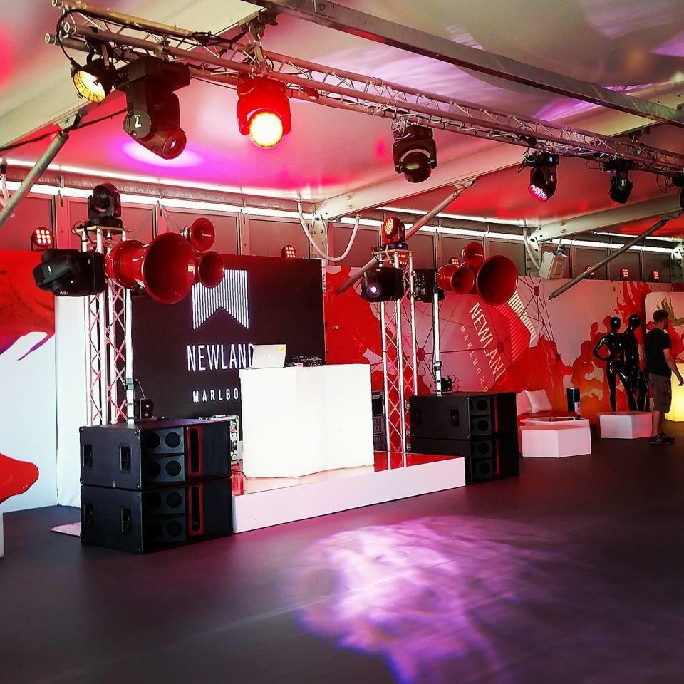 Scena eventowa z nagłośnieniem tubowym, oświetleniem punktowym i dekoracją w kolorze czerwonym z logo NEWLAND MARLBO.