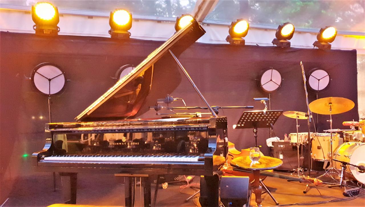 Scena z pianinem Steinway & Sons, perkusją i oświetleniem scenicznym skierowanym na instrumenty muzyczne, przygotowana do występu.