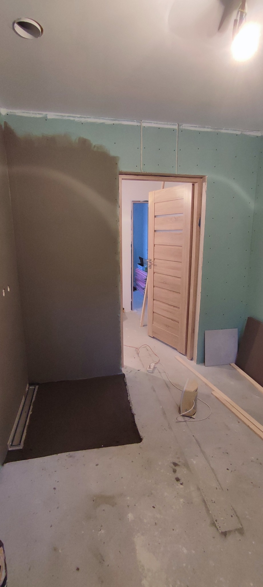 Przygotowanie do wykończenia łazienki: ściany obłożone płytami gipsowo-kartonowymi, wylewka pod prysznic z odpływem liniowym, drewniane listwy przypodłogowe, drzwi wewnętrzne z jasnego drewna...