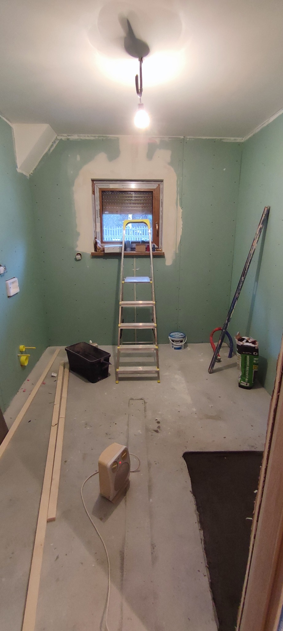 Wnętrze w trakcie przygotowań do prac wykończeniowych w Gliwicach, ściany pokryte płytami gipsowo-kartonowymi, drabina stojąca przy oknie, widoczne narzędzia i materiały budowlane.