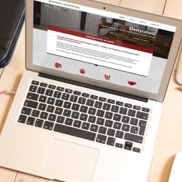 Studio Websteady - Laptop MacBook Air wyświetlający stronę internetową Harmony Properties na drewnianym biurku obok tabletu graficznego Wacom i czarnego skórzanego etui.