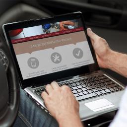 Studio Websteady - Osoba w samochodzie korzysta z laptopa, na ekranie strona internetowa z informacjami o oszczędzaniu na paliwie LPG, widoczne menu strony: Strona Główna, Nasze Usługi, Dlaczego LPG?, Cennik, Mapa...