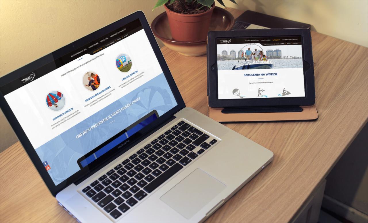Laptop i tablet prezentujące responsywną stronę internetową firmy oferującej szkolenia parasailingowe i obsługę eventów, widok z góry na drewnianym biurku.