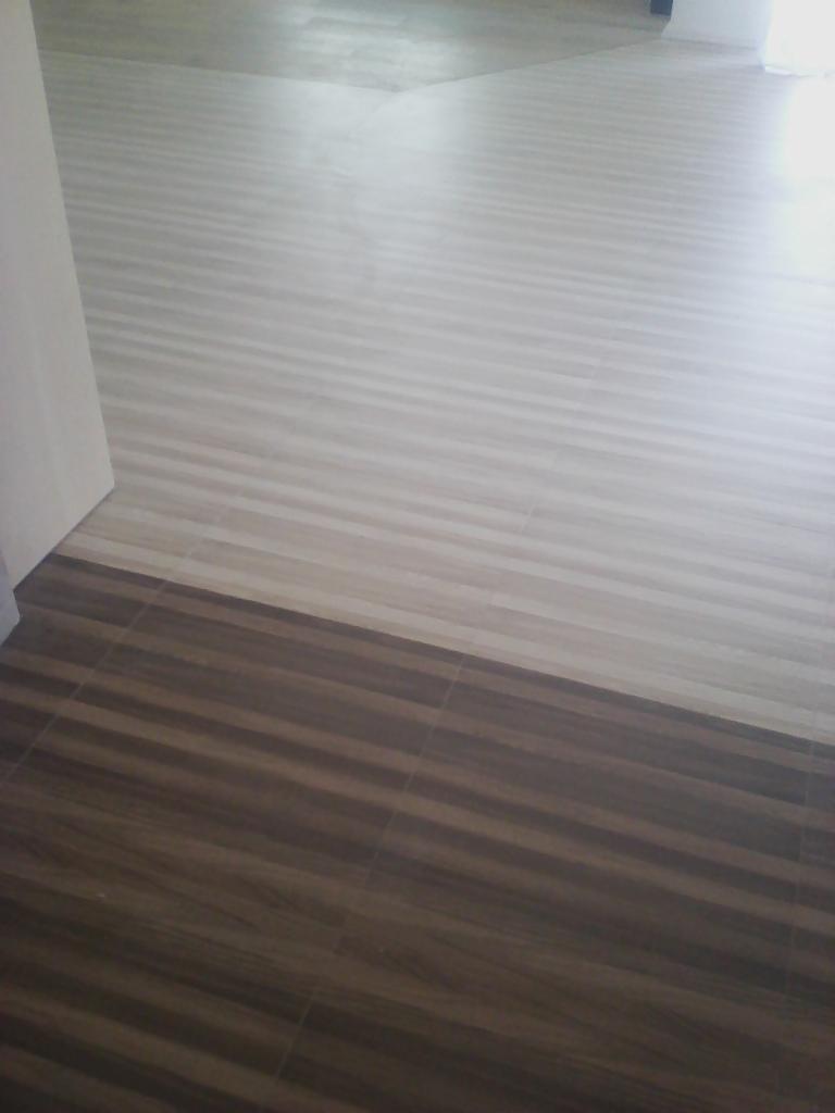 Ułożona podłoga z dwóch rodzajów płytek imitujących drewno: jaśniejsze, kremowe i ciemniejsze, brązowe, ułożone poziomo względem kadru.