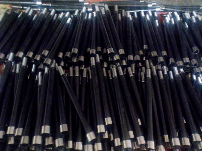 Stos czarnych, elastycznych przewodów z metalowymi końcówkami, ułożonych chaotycznie, widoczne ślady obróbki mechanicznej na końcówkach.