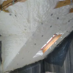 Poddasze ocieplone białą pianką PUR, widoczne drewniane elementy konstrukcji oraz otwór okienny