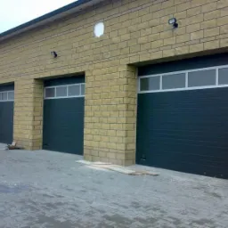 Trzy segmentowe w kolorze grafitowym z oknami, zamontowane w budynku z elewacją z jasnej cegły, widoczne z zewnątrz.