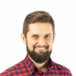 Uśmiechnięty, brodaty mężczyzna w czerwonej koszuli w kratę na białym tle. Portret pracownika IT, prawdopodobnie programisty lub specjalisty od baz danych.