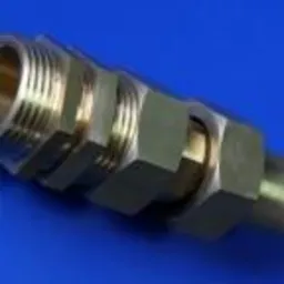 Mosiężny element z gwintem i nakrętkami sześciokątnymi, precyzyjnie wykonany, na niebieskim tle.