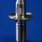 Precyzyjnie obrobiony metalowy element z gwintem, kołnierzem i sześciokątnym wycięciem, na jednolitym niebieskim tle, ukazujący detale obróbki.