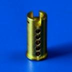 Mosiężny element cylindryczny z precyzyjnie wykonanymi otworami i nacięciem na górze, sfotografowany na jednolitym niebieskim tle.