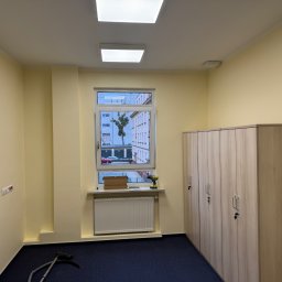 Remokompleks Michał Motyl - Pomieszczenie po malowaniu ścian na jasnożółty kolor. Widoczne szafy, okno, grzejnik, narzędzia i odkurzacz. Na ścianie gniazdka elektryczne.