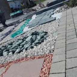 Ekspozycja r&oacute;żnych rodzaj&oacute;w nawierzchni: kostka brukowa szara, granitowa szara, płyty kamienne brązowe, biały i kolorowy żwir dekoracyjny, szklane elementy dekoracyjne imitujące strumień.