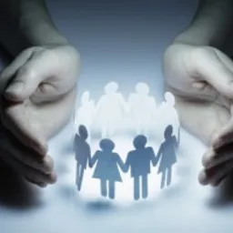 Dłonie otaczające krąg z papierowych figurek ludzi, symbolizujące ochronę i wsparcie społeczności.