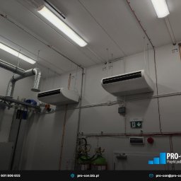 PRO-CON SERWIS Klimatyzacja Wentylacja Rekuperacja - Dwa białe klimakonwektory podwieszone pod sufitem w pomieszczeniu technicznym z widocznymi instalacjami wentylacyjnymi i przeciwpożarowymi.