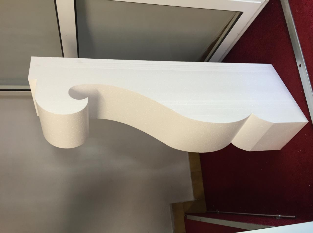Dekoracyjny element architektoniczny z białego styropianu o falistym kształcie, prawdopodobnie listwa przysufitowa.