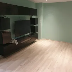 Nowoczesny salon z brązowymi meblami na ścianie w kolorze miętowym, jasna podłoga laminowana, widok z perspektywy podłogi.