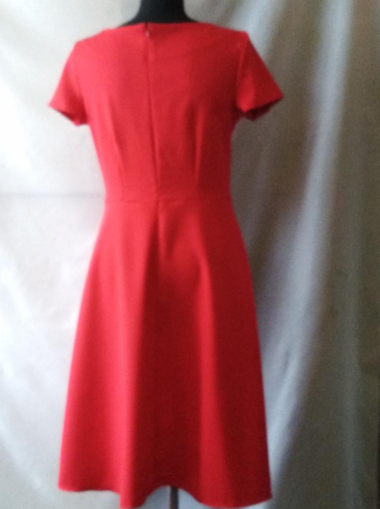Czerwona, dopasowana sukienka z krótkim rękawem, widok z tyłu, na manekinie, z delikatnym marszczeniem w talii.