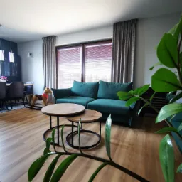 Salon z zieloną sofą, drewnianym koniem na biegunach, stolikami kawowymi i zasłoniętymi żaluzjami oknami.