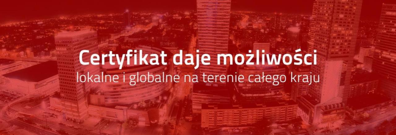 Panorama miasta z wieżowcami w czerwonej tonacji, z nałożonym tekstem: Certyfikat daje możliwości lokalne i globalne na terenie całego kraju.