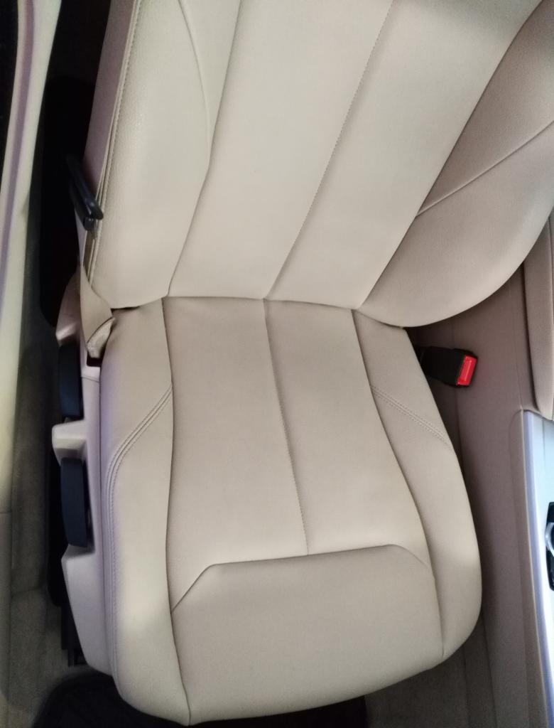 Jasne, skórzane siedzenie samochodowe z widocznym pasem bezpieczeństwa i elementami regulacji, sfotografowane z góry pod kątem.