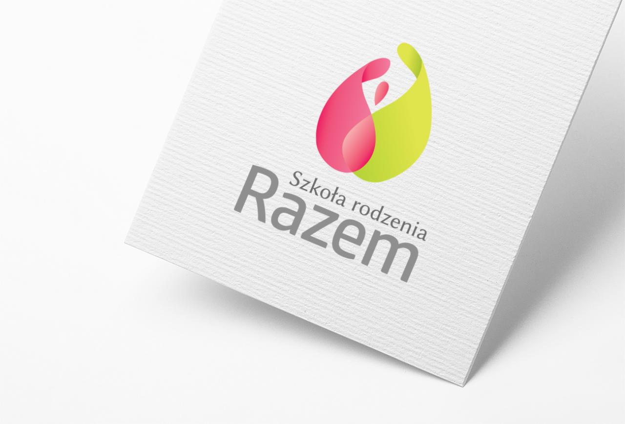 Logo 'Szkoła Rodzenia Razem' na wizytówce z teksturą papieru, z gradientowym symbolem w kształcie łzy w kolorach różu i zieleni.
