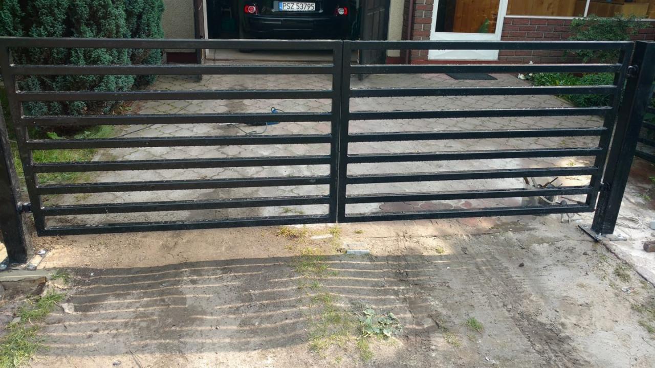 Brama posesyjna z poziomych profili pomalowana na czarno, zrealizowana w Szamotułach, widoczna na tle podjazdu i zieleni.