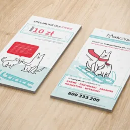 Dwie ulotki reklamowe sklepu zoologicznego Max&Mrau z ilustracjami psa i kota na saniach, oferujące rabat 10 zł i informujące o ofercie karm, przysmaków, zabawek, kosmetyków i witamin.