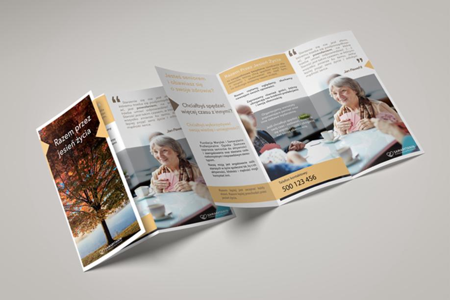 Trójdzielna broszura informacyjna leżąca na szarym tle, prezentująca ofertę opieki dla seniorów, z widoczną grafiką jesiennego krajobrazu i zdjęciami uśmiechniętych seniorów przy stole.