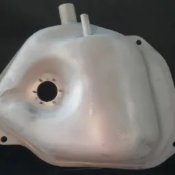 Metalowy zbiornik paliwa po obróbce, widoczne otwory montażowe i wloty, powierzchnia matowa, przygotowana do dalszej obróbki lub malowania.